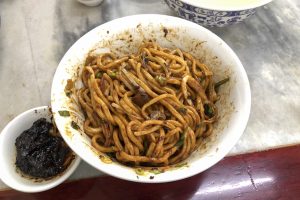 Bowl of Beijing zhajiangmian noodles mixed with fried soybean paste sauce