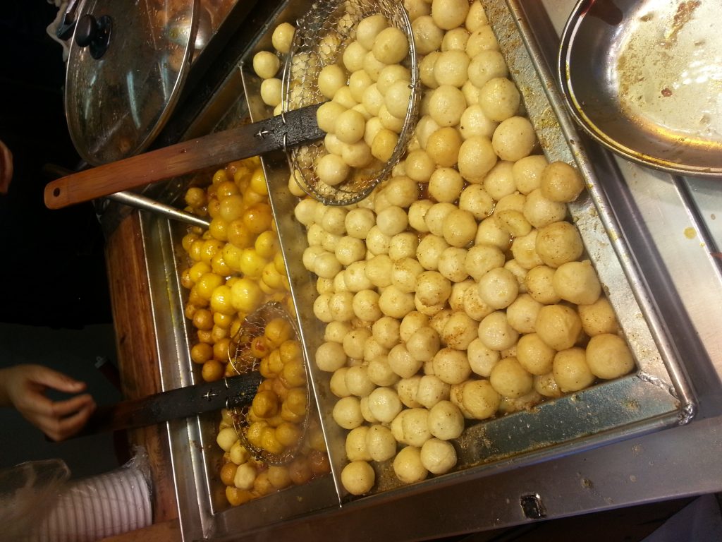 Trays of fresh Chinese fish balls at a busy stall with wire strainers