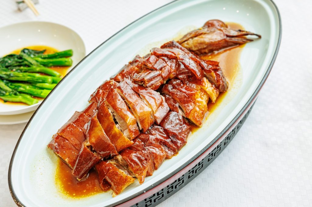 Chopped Cantonese roast goose with crisp amber skin arranged on a platter