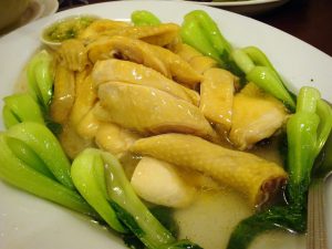 Cantonese white cut chicken sliced and served with greens and broth