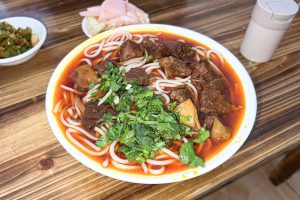 Bowl of Guizhou-style braised beef rice noodles in reddish broth, a related Guiyang-region noodle scene for changwang travellers