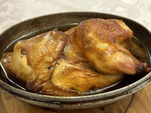 Whole Hangzhou Beggar's Chicken glazed golden-brown in a metal serving dish