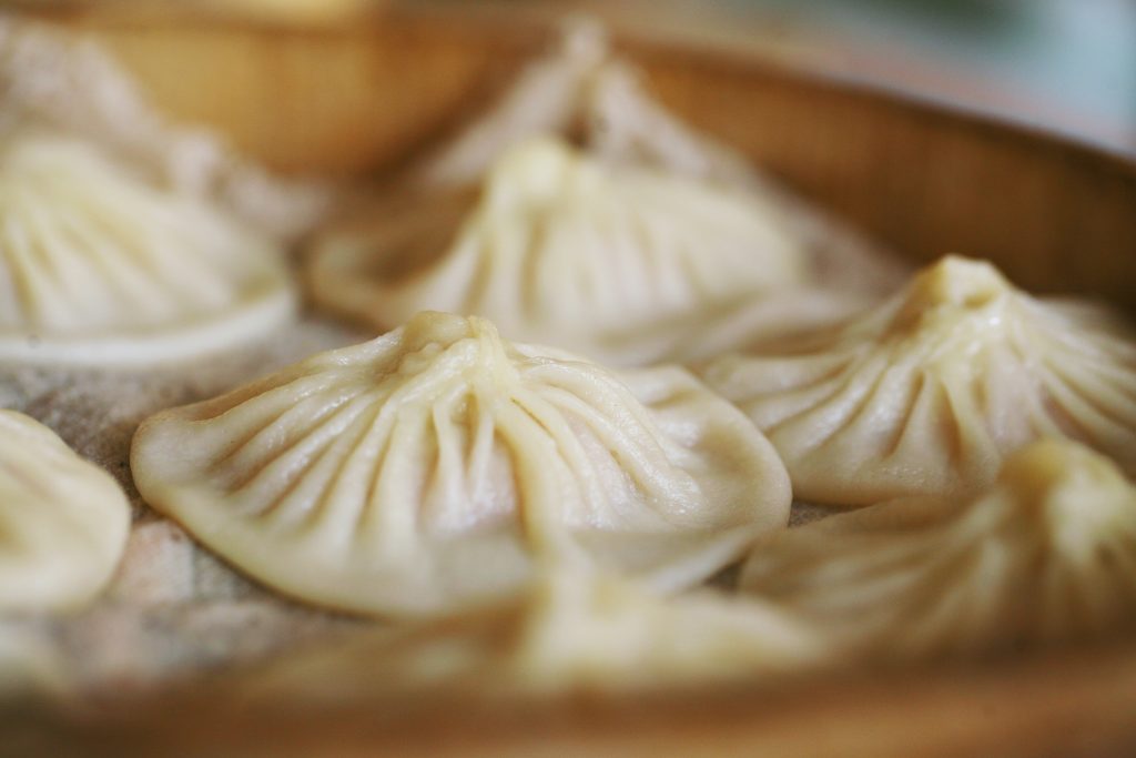 Steamed Kaifeng soup dumplings with fine pleats in a bamboo steamer