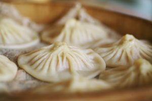 Steamed Kaifeng soup dumplings with fine pleats in a bamboo steamer