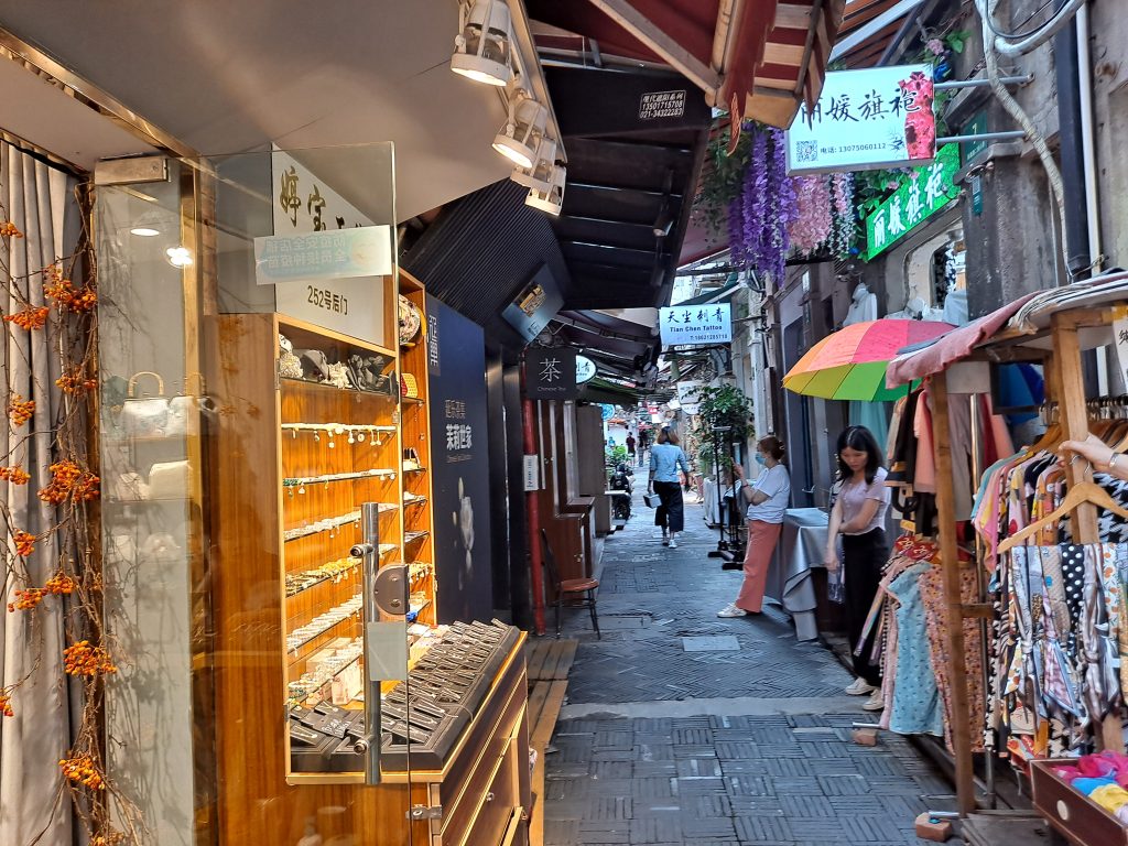 Narrow shikumen lane with shops and hanging signs in Shanghai’s Tianzifang