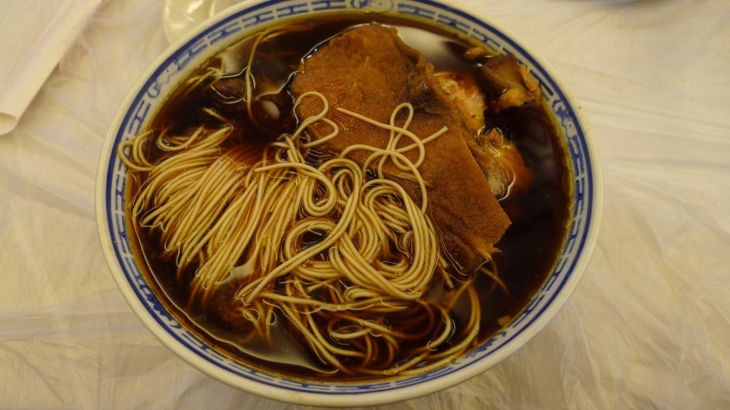Bowl of Suzhou Kunshan Aozao noodles with dark broth and braised topping