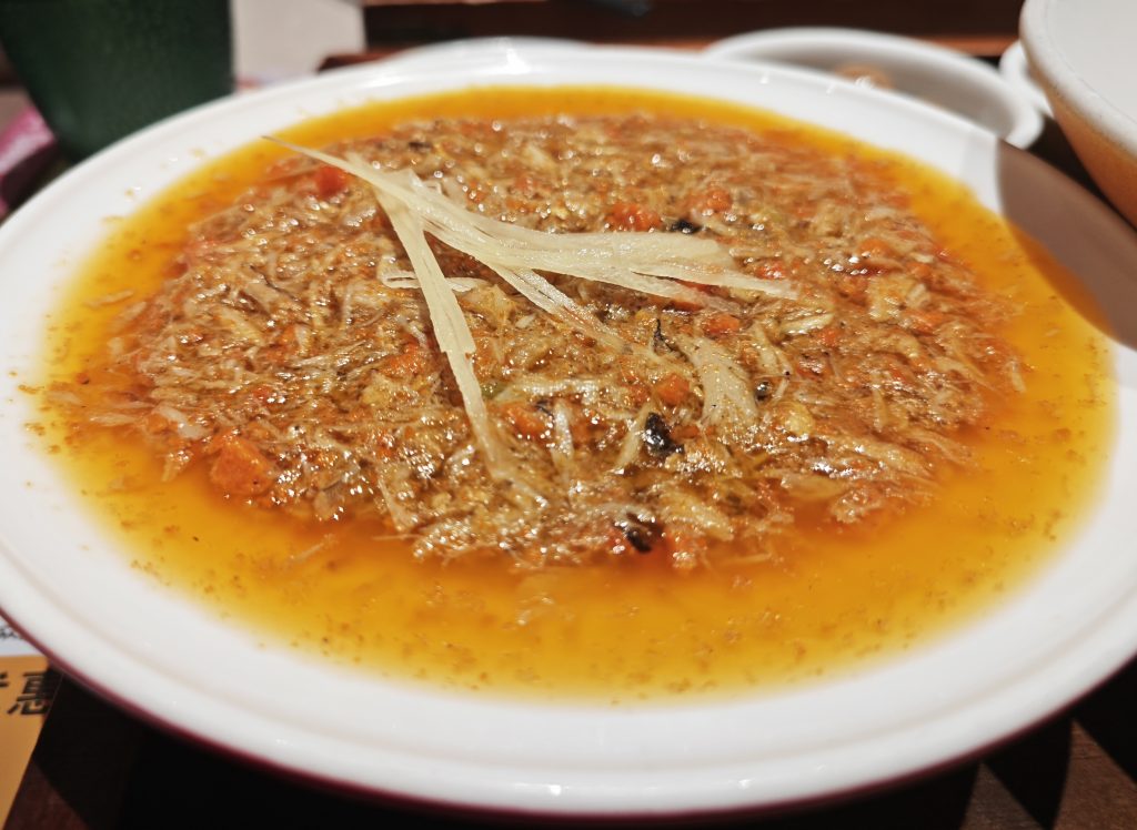 Bowl of Suzhou crab roe noodles with orange crab paste topping and wheat noodles