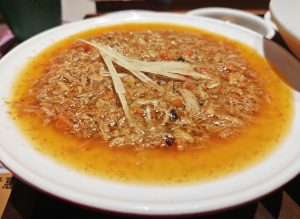 Bowl of Suzhou crab roe noodles with orange crab paste topping and wheat noodles