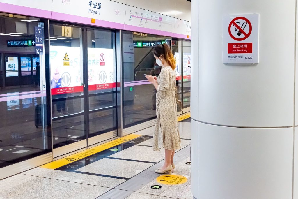 Passenger using a smartphone while waiting at a Beijing metro station platform