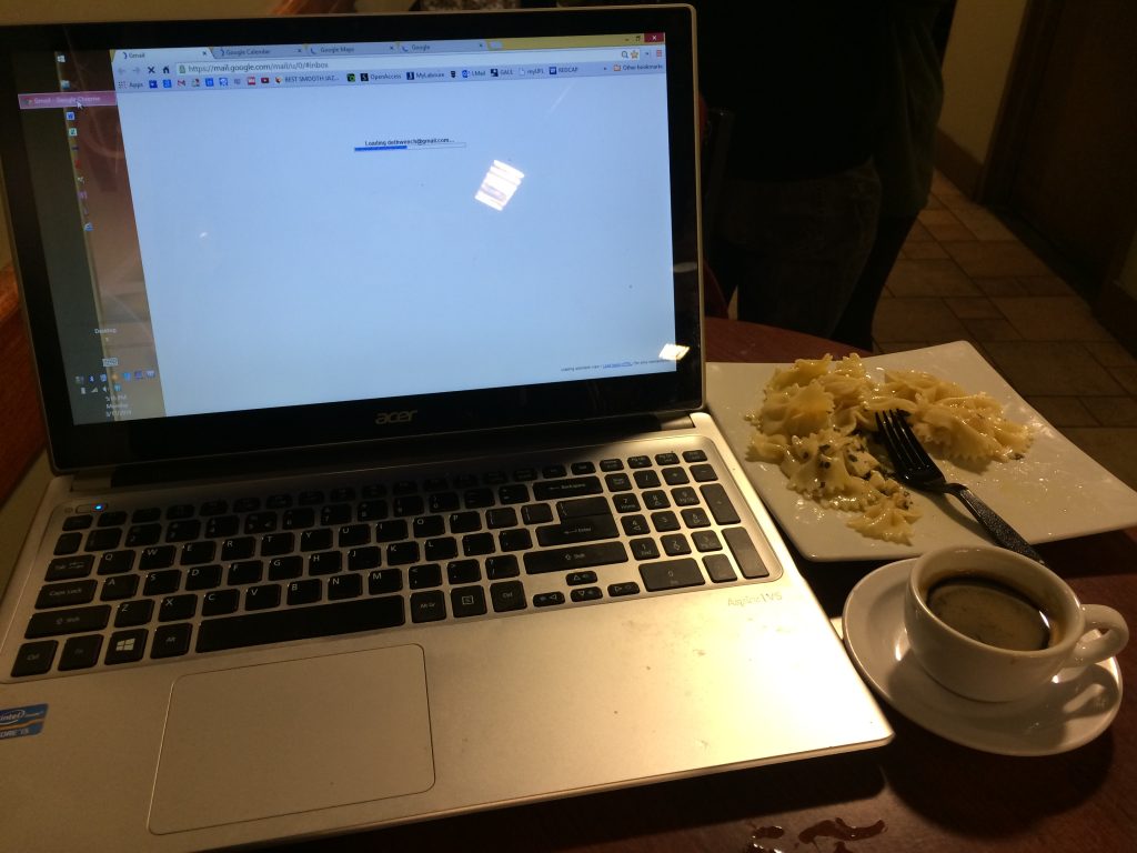 Open laptop on a cafe table beside food and a drink