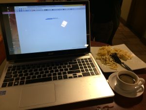 Open laptop on a cafe table beside food and a drink