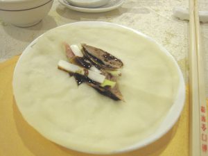 Peking duck pancakes with crispy skin, scallions, and sauce on a restaurant table