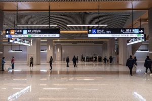 Busy Beijing subway transfer corridor with bilingual signs and passengers