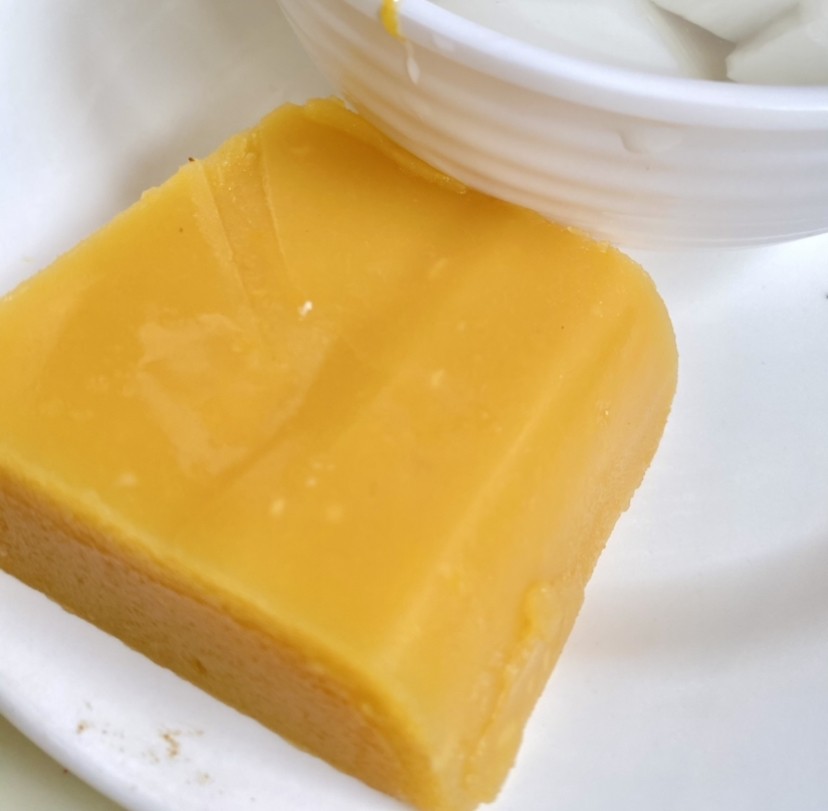 Smooth golden-yellow block of wandouhuang, Beijing pea flour cake, on a white plate