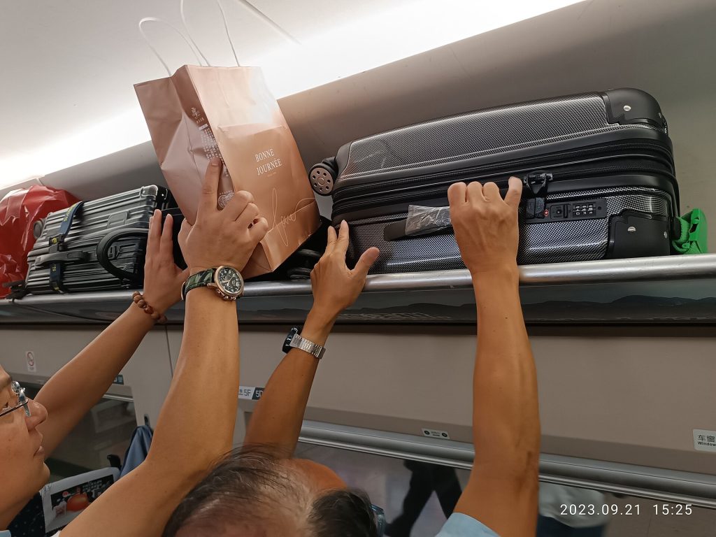 High-speed train departing a Chinese station with travellers and luggage on the platform