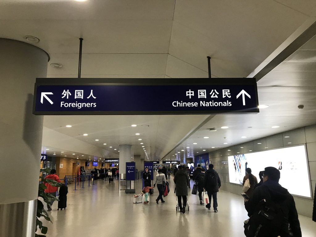 Overhead immigration sign at Shanghai Pudong International Airport directing arriving passengers to separate lanes for foreigners and Chinese nationals
