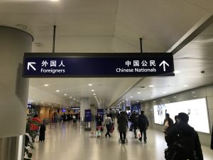 Overhead immigration sign at Shanghai Pudong International Airport directing arriving passengers to separate lanes for foreigners and Chinese nationals