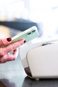 Smartphone contactless payment held near a store card terminal