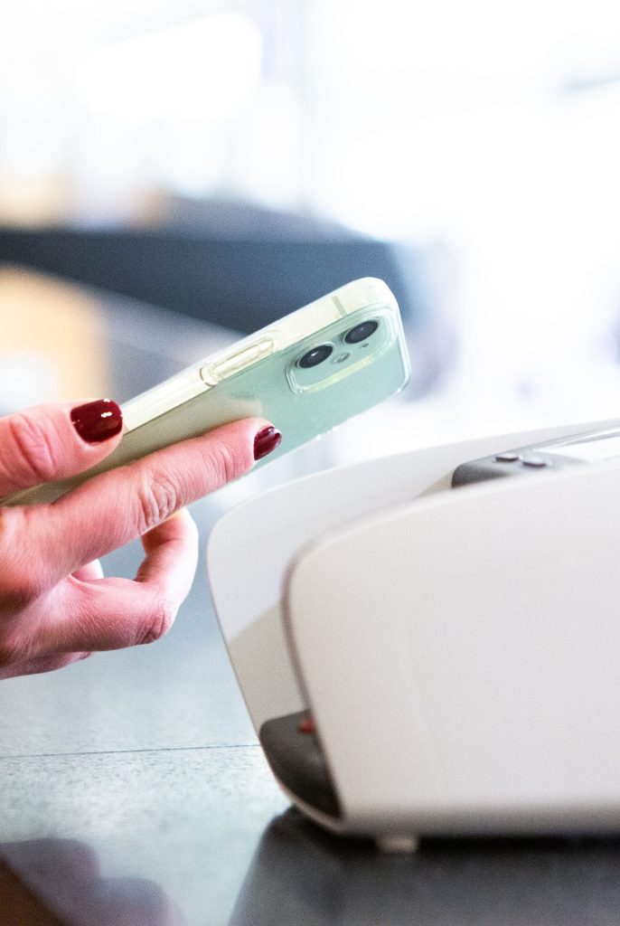 Smartphone contactless payment held near a store card terminal