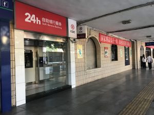 Bank ATM screen and foreign bank card held in a city street at dusk
