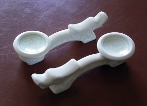 Pair of wooden chopsticks resting on a ceramic holder beside a bowl