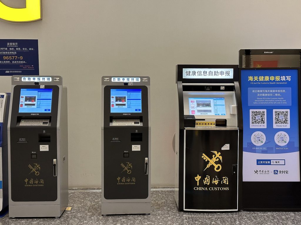 Airport customs inspection channel signs above arriving passenger queues