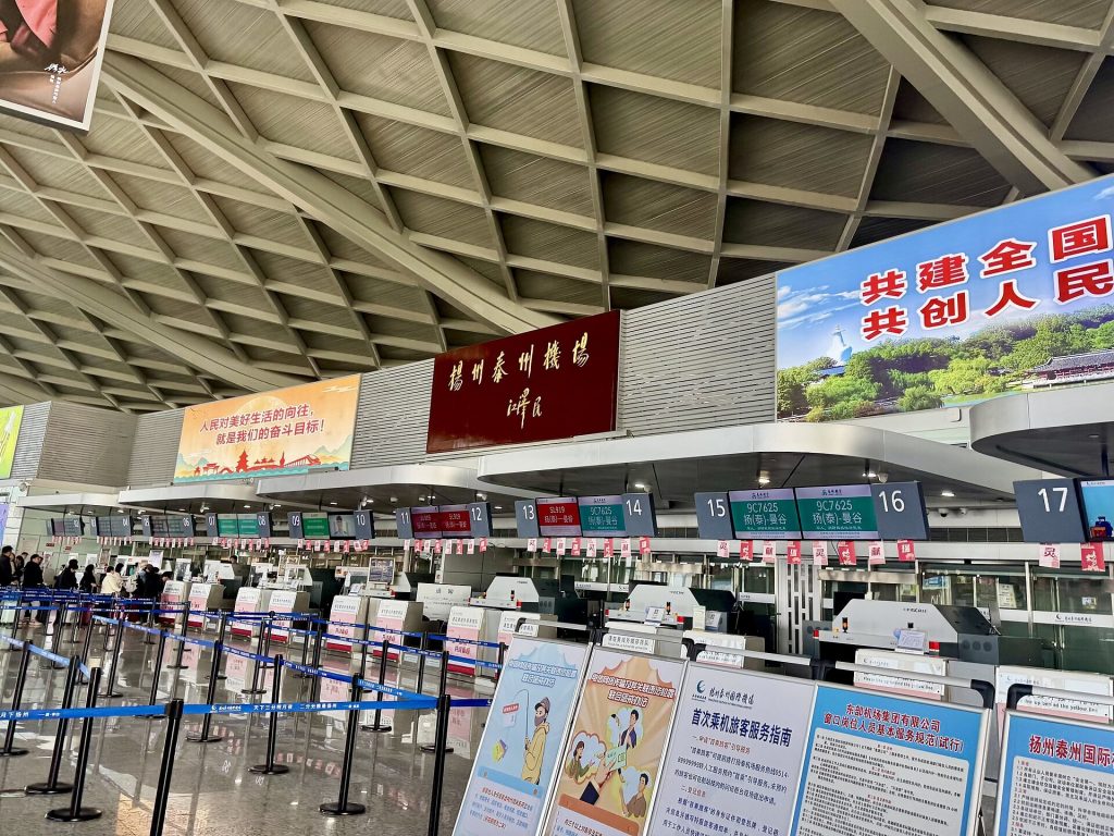 Airport check-in hall with departure boards and queues