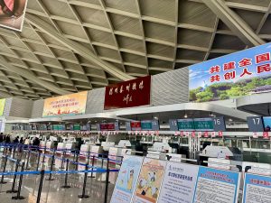 Airport check-in hall with departure boards and queues