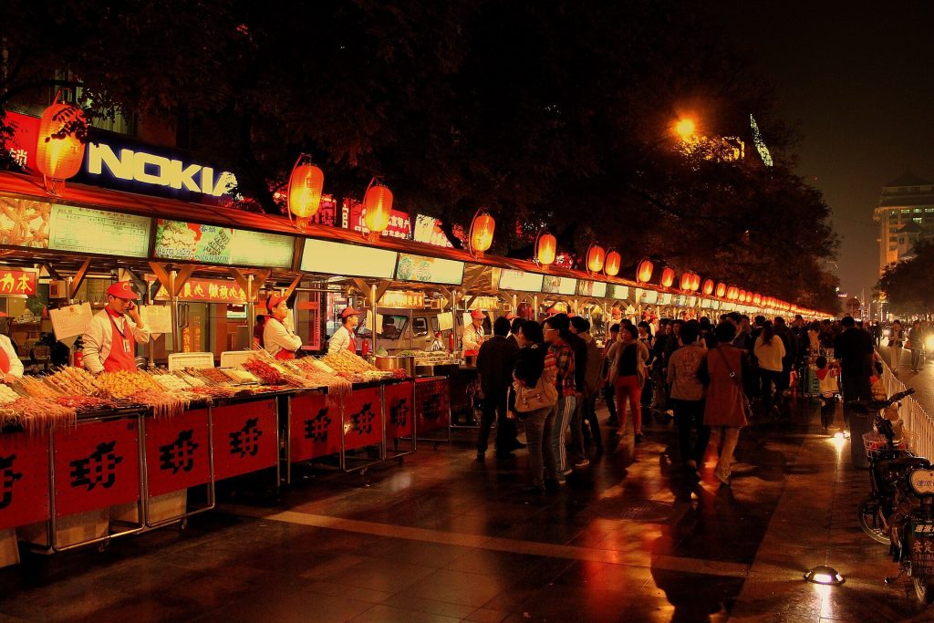 Busy Chinese night market street with food stalls and warm lights