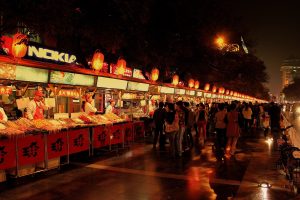 Busy Chinese night market street with food stalls and warm lights