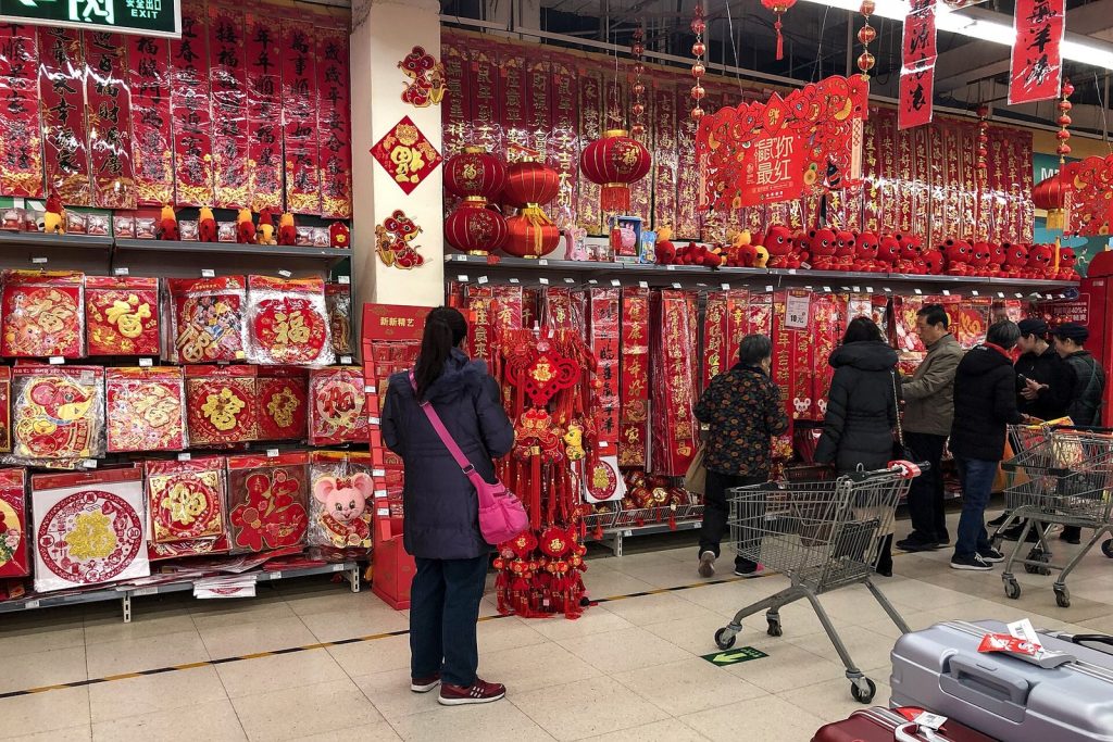 Shoppers browsing shelves of red Chinese New Year couplets, lanterns and decorations inside a Beijing supermarket