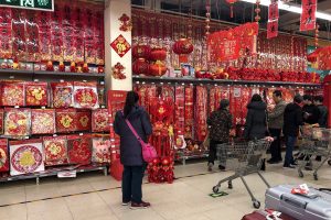 Shoppers browsing shelves of red Chinese New Year couplets, lanterns and decorations inside a Beijing supermarket