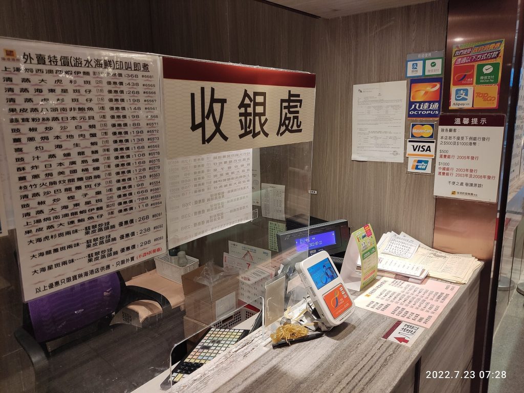 Cashier scanning a customer phone QR code at a small shop counter