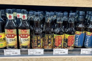 Supermarket shelf in Beijing lined with bottles of Shanxi mature vinegar from several brands, with price tags below