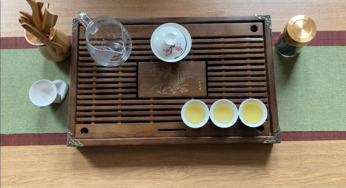Gaiwan and tea cups on a wooden tea tray in a quiet teahouse