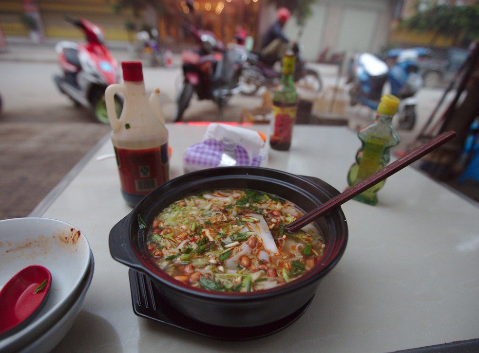 Bowl of Chongqing xiaomian noodles with chili oil, peanuts, and green onions