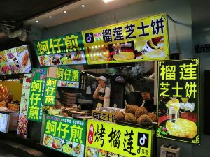 Night-market stall in Xiamen Zeng Cuoan preparing Fujian-style oyster omelette on a flat griddle