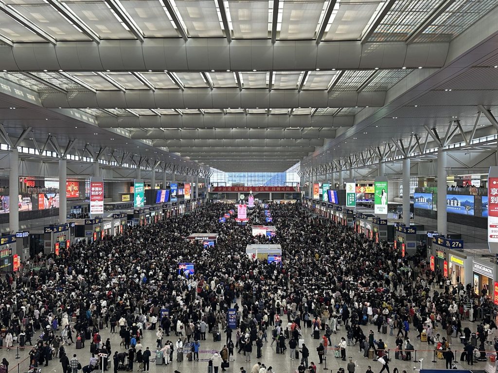 Crowded waiting hall concourse at Shanghai Hongqiao Railway Station with travelers under a long glass roof