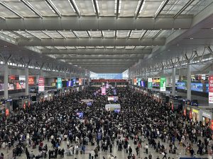 Crowded waiting hall concourse at Shanghai Hongqiao Railway Station with travelers under a long glass roof