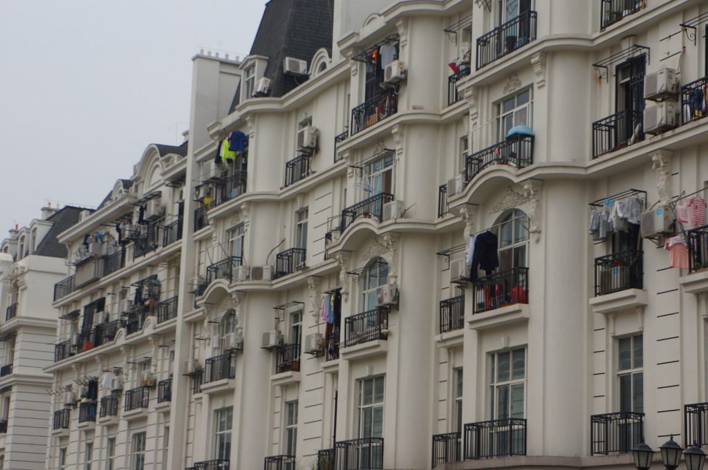 Laundry hanging out to dry on the balconies of a cream-coloured apartment building in China