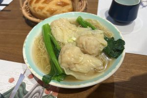 Bowl of Cantonese wonton noodles in clear broth with greens