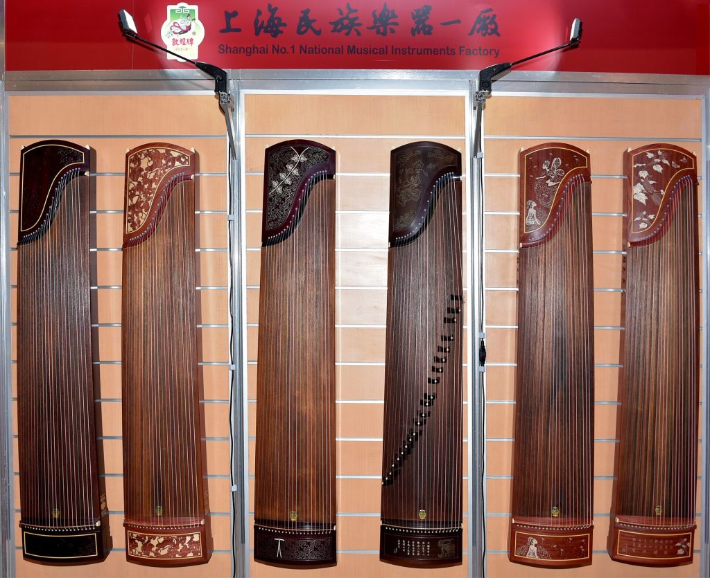 Musician playing a guzheng Chinese zither on a wooden stand