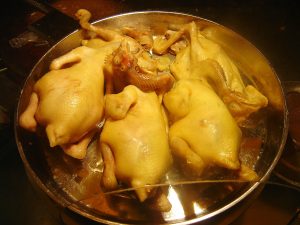 Plate of Hainan Wenchang chicken chopped into pieces with pale skin and ginger-scallion accompaniment