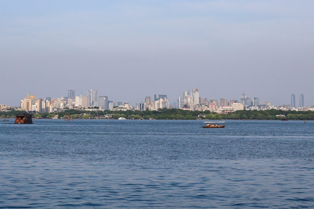 Hangzhou West Lake willow-lined shore with boats in soft morning light