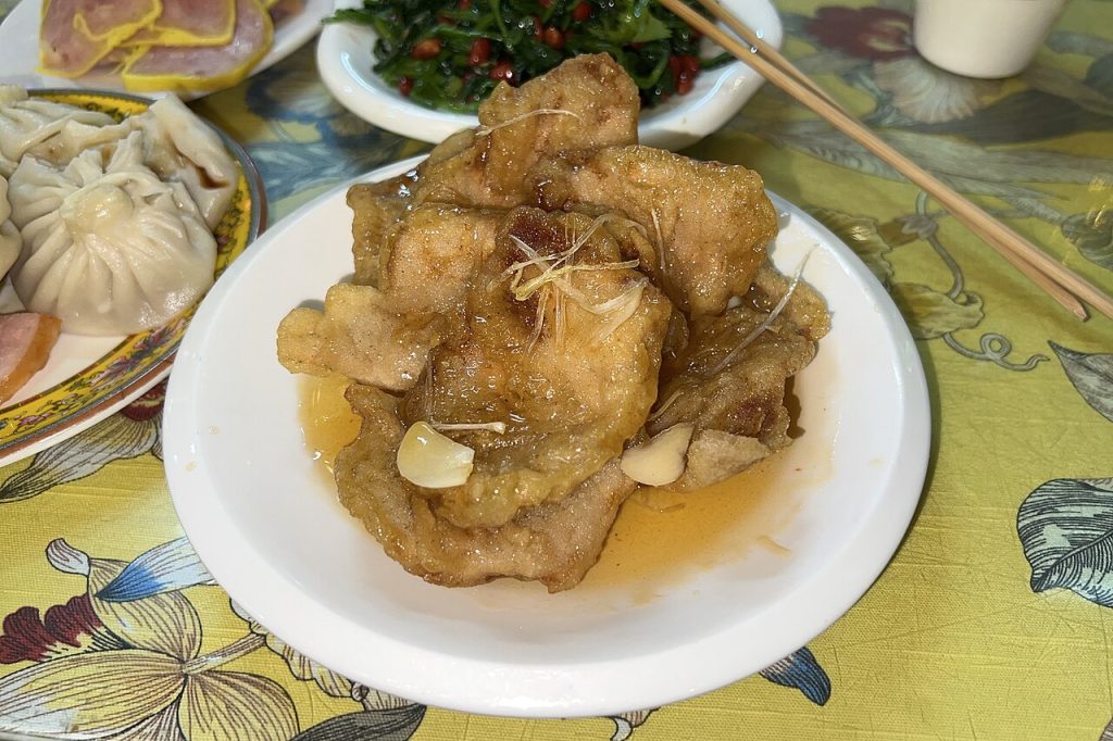 Plate of Northeast-style guobaorou sweet-and-sour fried pork slices with glossy sauce and garnish