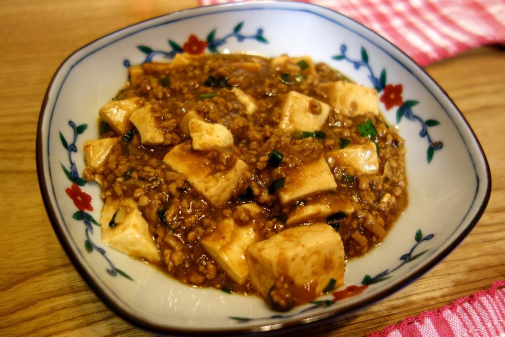 Plate of mapo tofu with chili oil and minced meat over soft tofu cubes