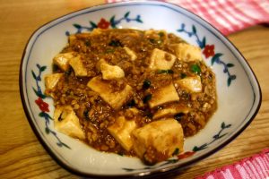 Plate of mapo tofu with chili oil and minced meat over soft tofu cubes