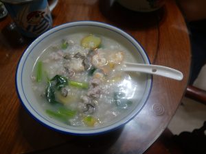 Bowl of Cantonese-style seafood congee topped with shrimp and greens