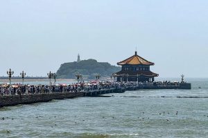 Qingdao seafront promenade at dusk with pier lights and calm autumn water