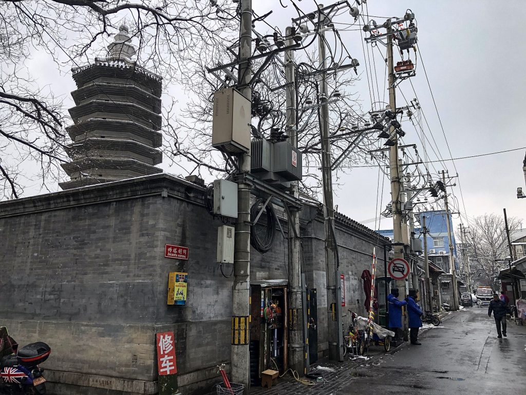 Quiet Beijing hutong lane with grey brick walls in morning light